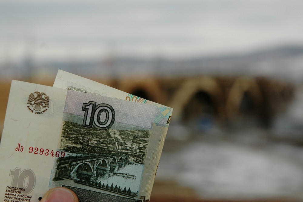 Десятирублевая купюра на фоне моста через Енисей в Красноярске