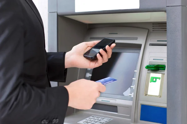 Бизнесмен стоял возле банкомата и проведения кредитной карты и — стоковое фото